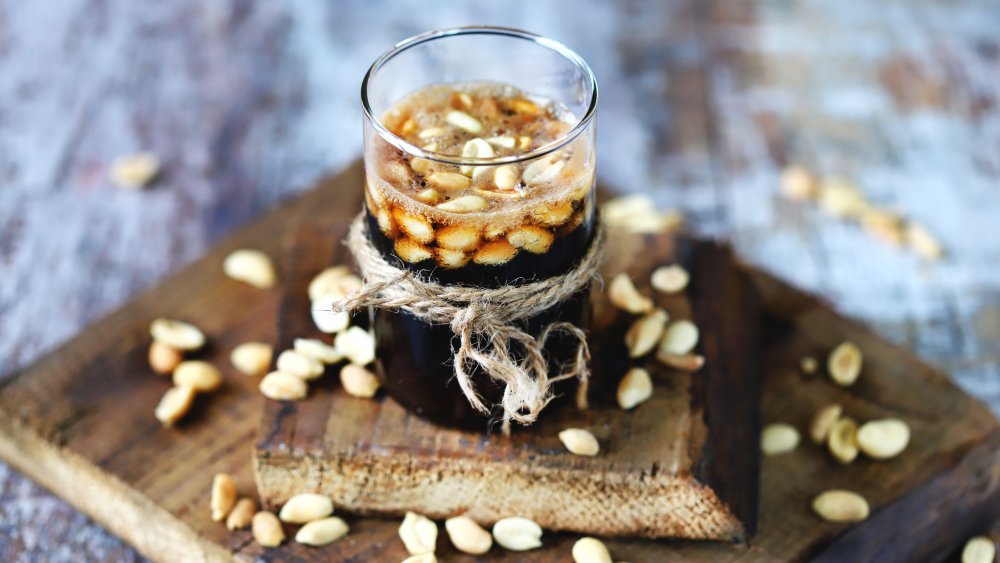 a glass of coke with peanuts in it