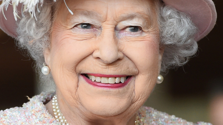 Queen Elizabeth II with wide smile and pink hat