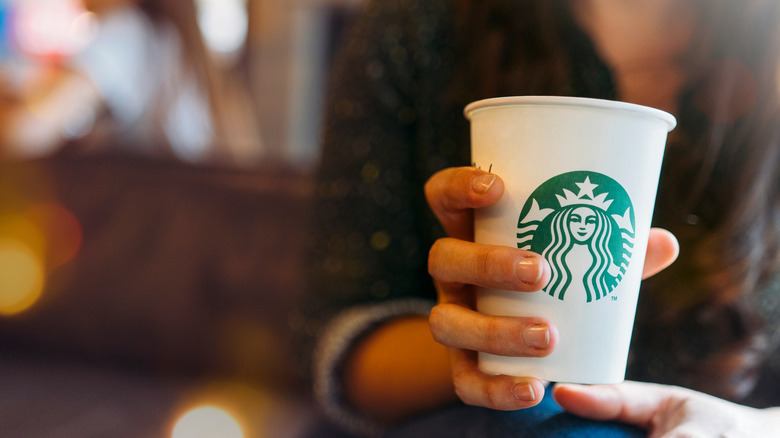 Person holding white Starbucks cup