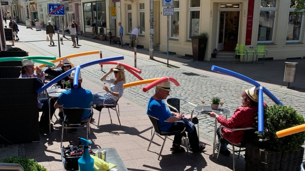 Patrons at German cafe wear pool toys on hats to encourage social distancing