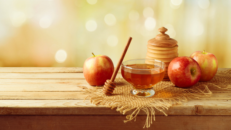 Apples and honey on wooden table