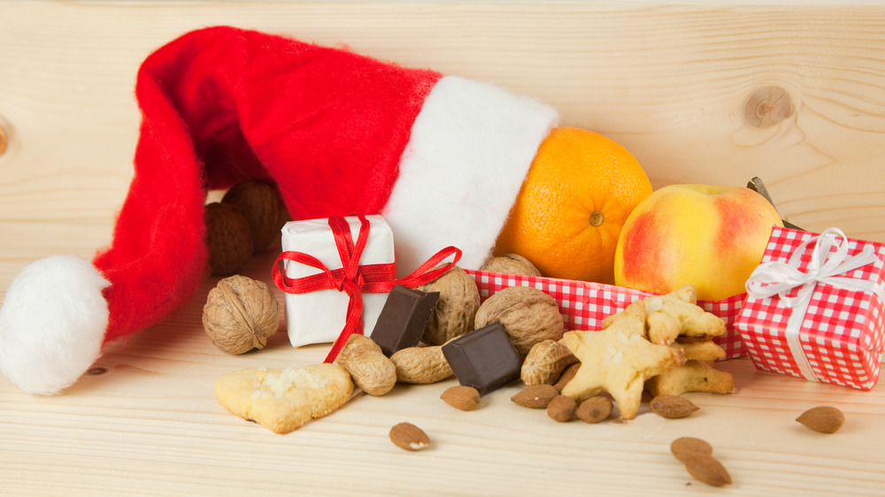 Orange, apple, chocolate, nuts, and cookies in a Santa hat