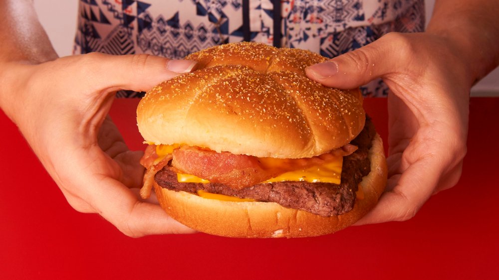 A woman holds a Wendy's burger