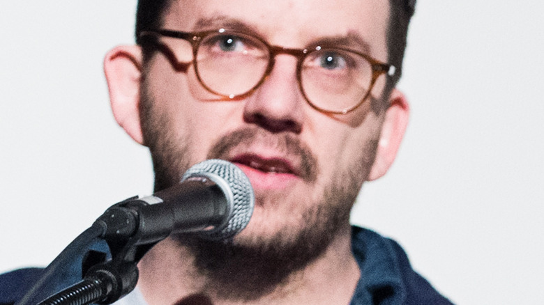 Peter Meehan speaks into microphone while wearing glasses