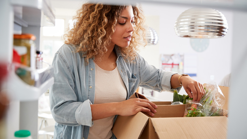 Woman with a box near her fridge