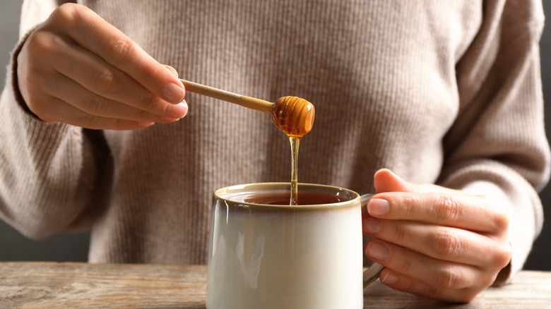 Woman putting honey in tea