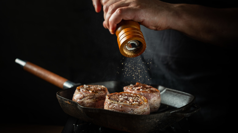 Steak in a pan being seasoned