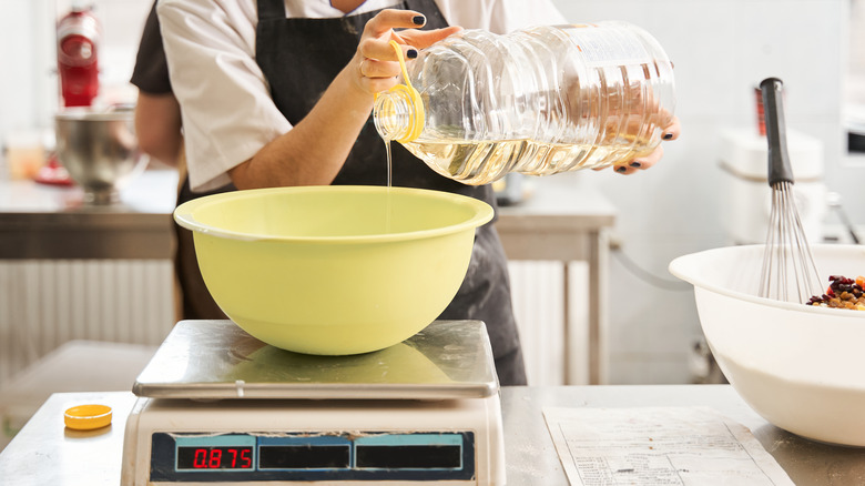 Woman pouring oil into bowl on scale