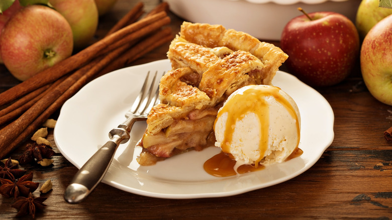 Slice of apple pie on white plate with vanilla ice cream