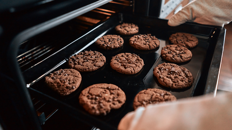 person taking cookies on a baking sheet out of the oven