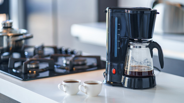 Coffee maker and cups on kitchen counter