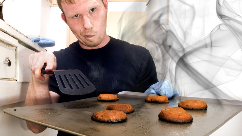 Man holding a baking sheet with burnt cookies 
