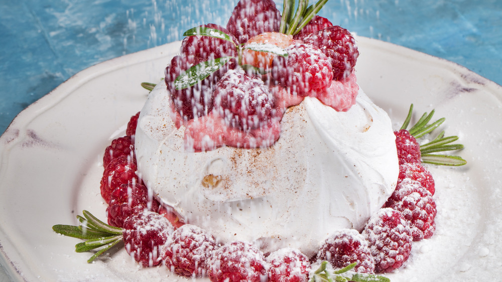 Pavlova topped with cream and raspberries