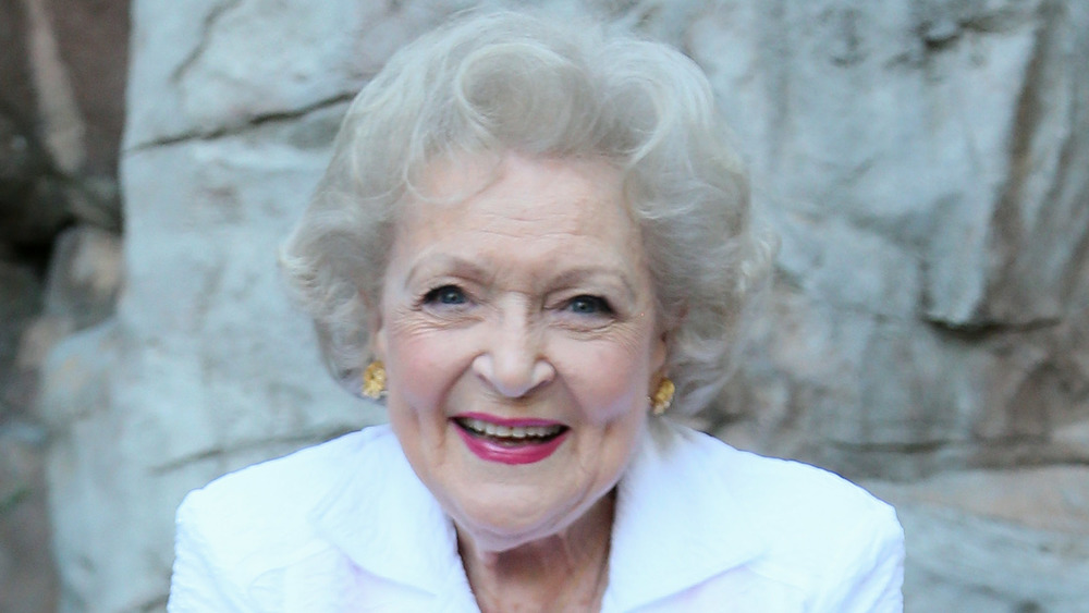 Betty White wearing gold earrings and a white blazer