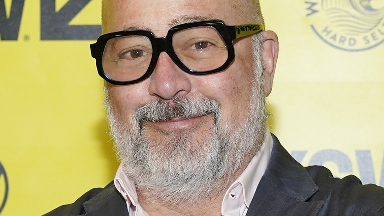 Andrew Zimmern with slight smile and thick glasses
