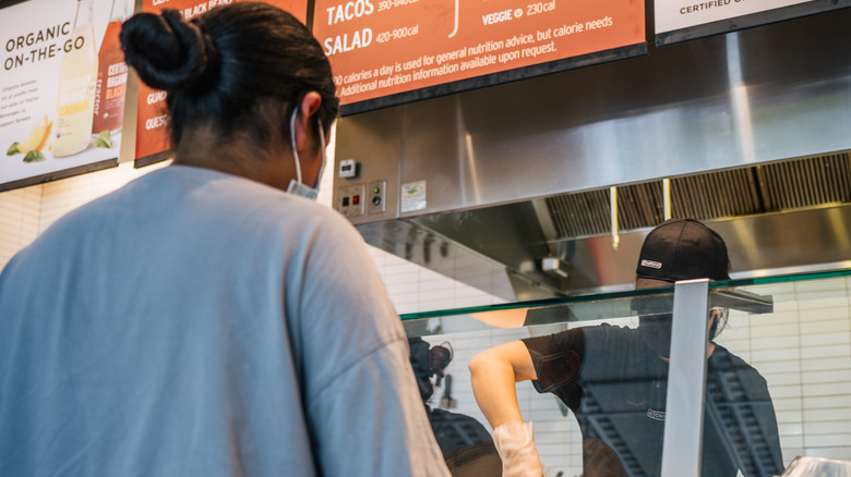Chipotle employee makes food behind glass