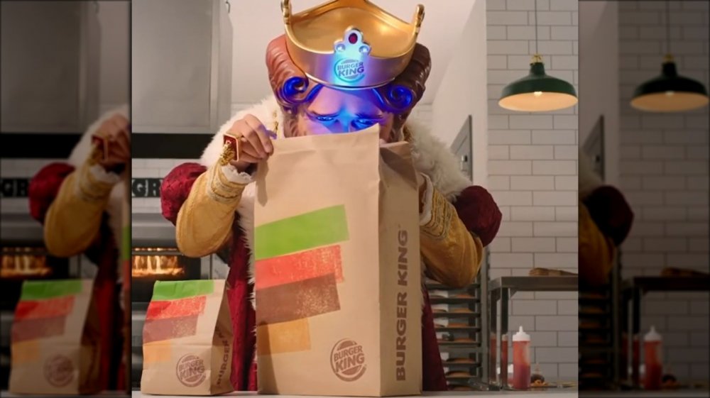 Burger King's newest ad featuring the King looking into a takeout bag. He's illuminated with a blue light