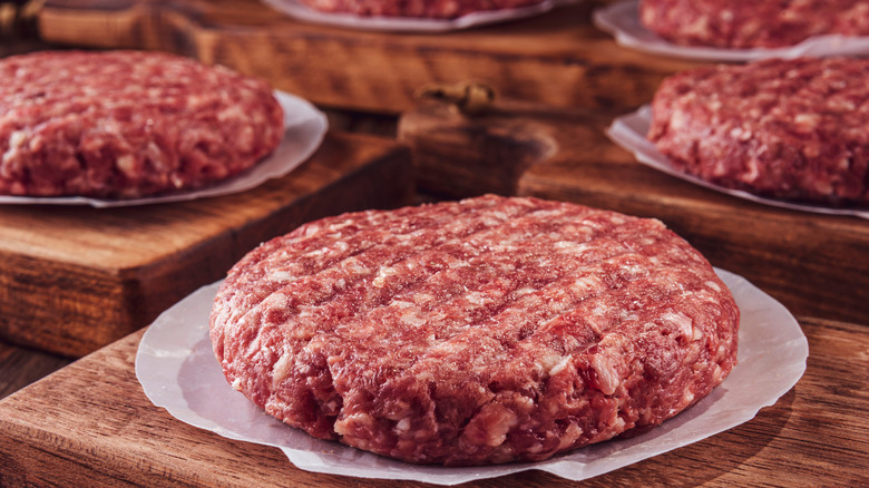 Ground hamburger meat on wooden boards
