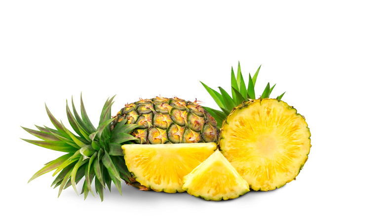Whole pineapple next to cut up pieces