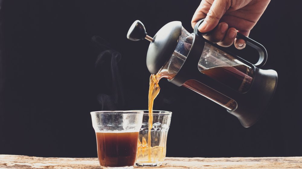 A French press pouring coffee into small glasses