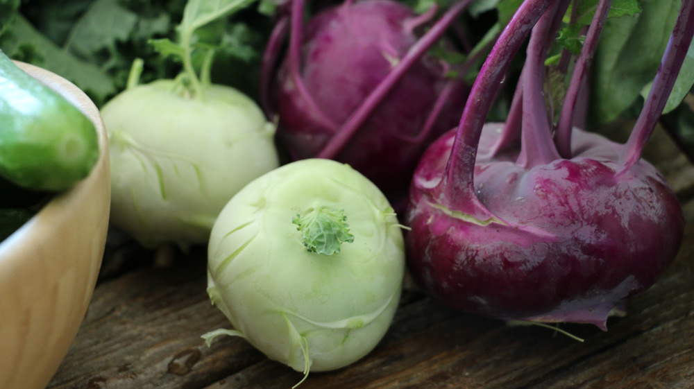 Purple and pale green kohlrabi on a wooden table