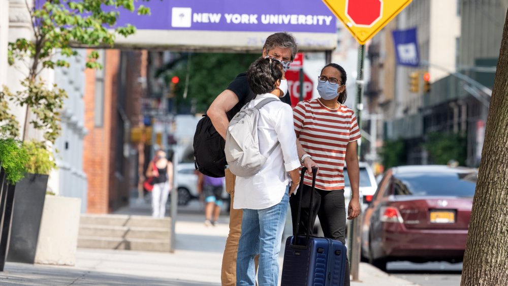 Masked NYU students gather outside of NYU building