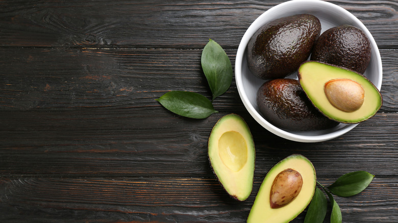 Halved avocados on wood table