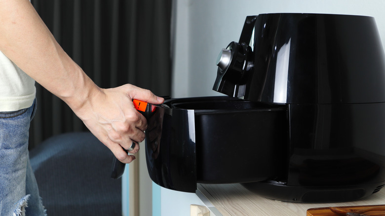 Man pulling air fryer drawer