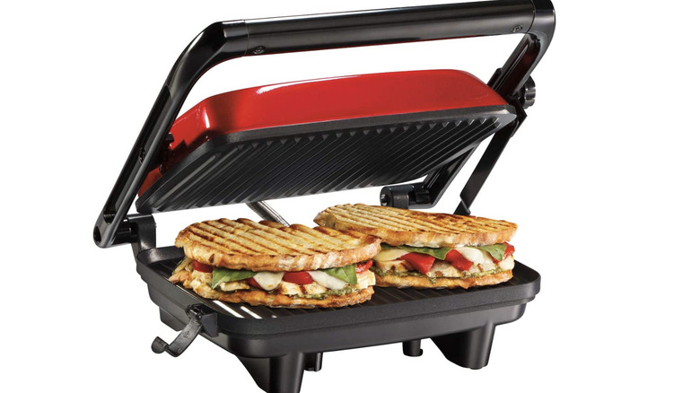 red panini press with two sandwiches cooking