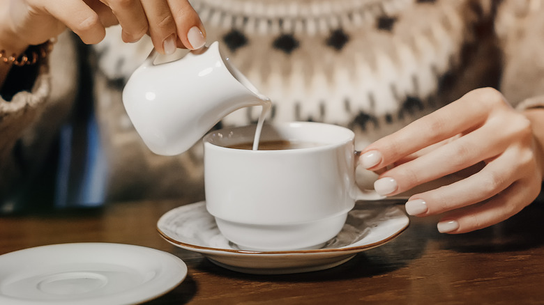 Person pouring a creamer into their coffee