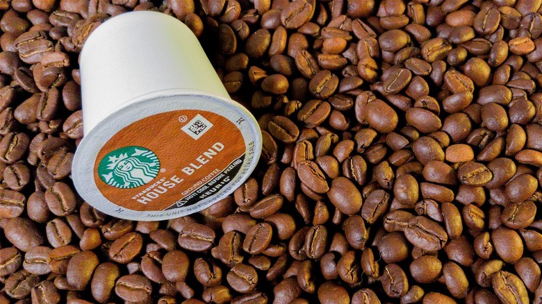 Starbuck K cup surrounded by coffee beans.