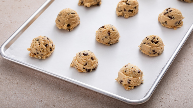 Mounds of raw chocolate chip cookie dough on baking sheet