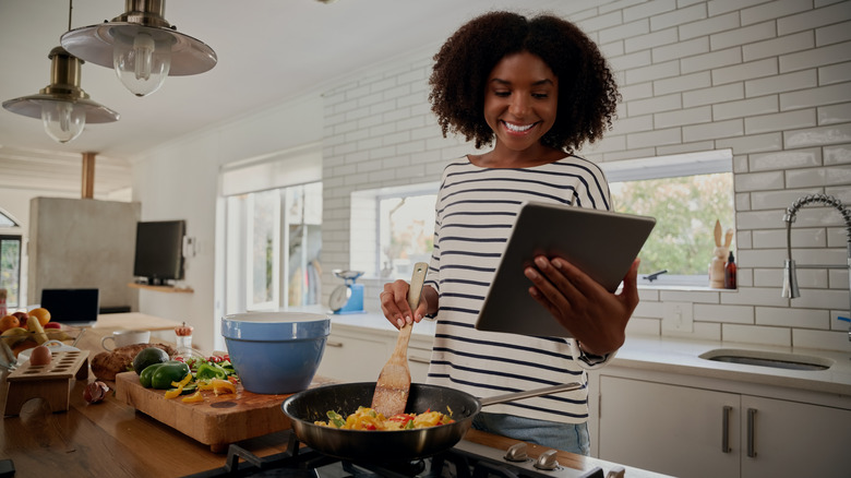 Woman looking at recipe while cooking