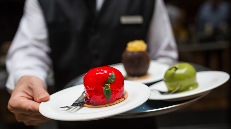 Waiter carrying plates of desserts