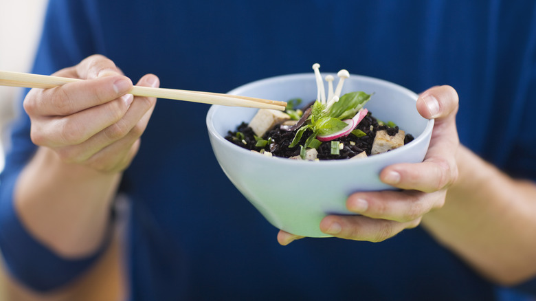 Person eating food with chopsticks