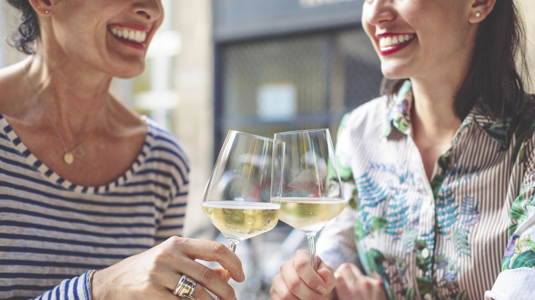 smiling mother and daughter drinking wine