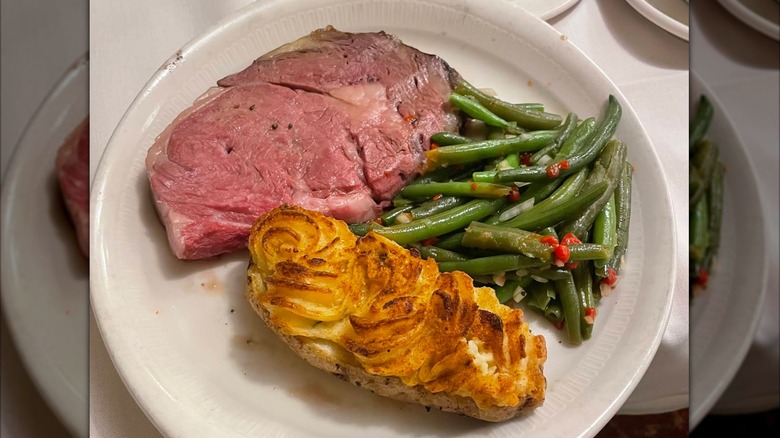 A slice of prime rib with green beans and a twice-baked potato