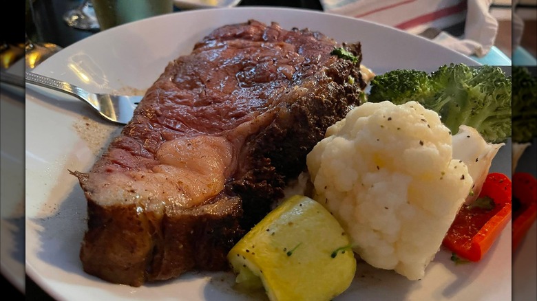 A slice of prime rib served with mixed vegetables