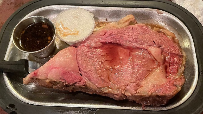 A massive slab of prime rib with a side of au jus and horseradish sauce