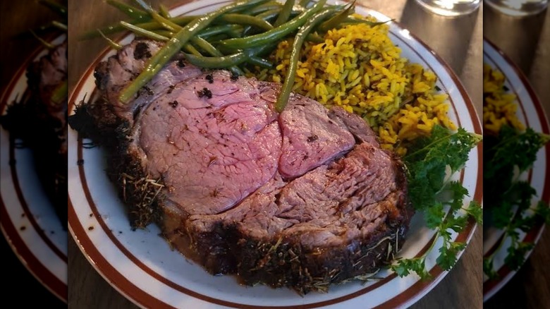 A piece of prime rib with green beans and rice