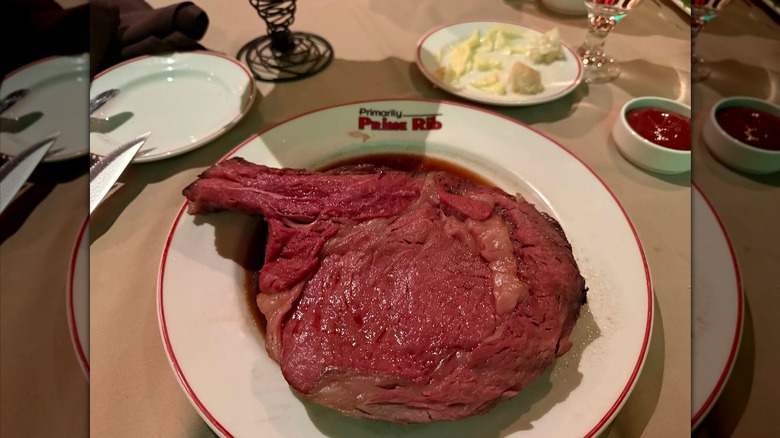 A large piece of rare prime rib on a plate that says Primarily Prime Rib