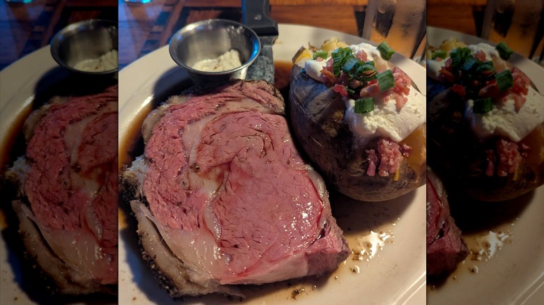 A piece of prime rib with a loaded baked potato