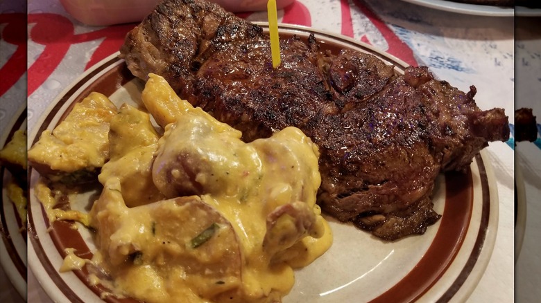 A piece of prime rib with a side of creamy potatoes