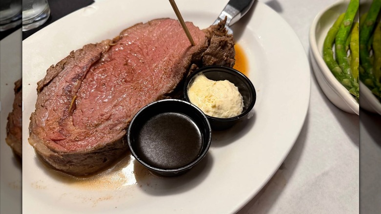 A slice of prime rib with au jus and horseradish sauce
