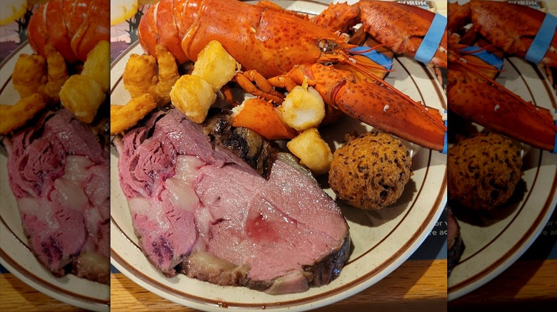 A slice of prime rib and a full lobster on a plate with a hushpuppy and fried shrimp