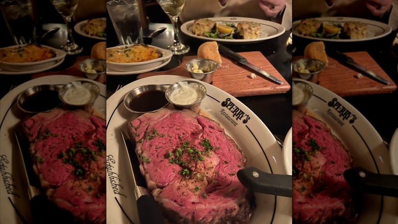 A large slab of pink prime rib on a plate that says Sperry's Restaurant with other dishes in the background