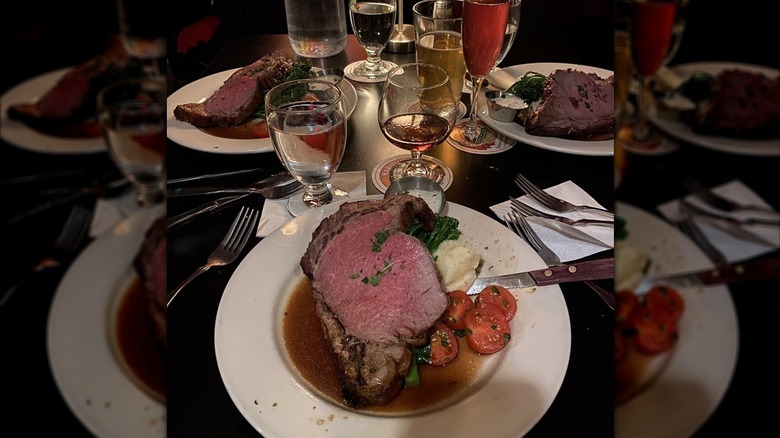 A slice of prime rib served with mashed potatoes and tomatoes
