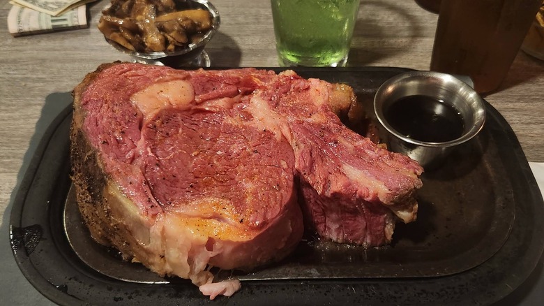 A think slice of prime rib served with au jus and mushrooms