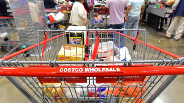 Costco cart with groceries and shoppers