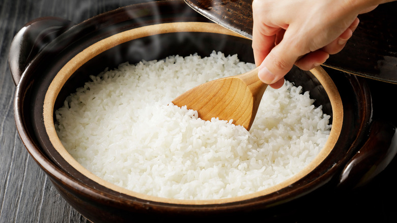 Person stirring rice with wooden spoon